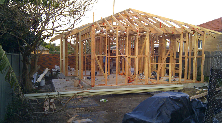 Kogarah studio addition mid-construction, timber roof and wall framing erected on the concrete slab