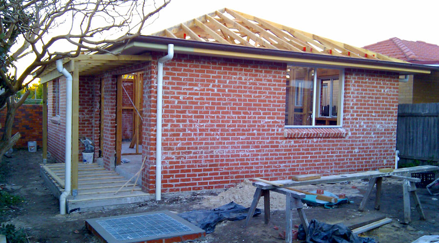Kogarah studio addition under construction, brick walls up with roof trusses and eaves being installed