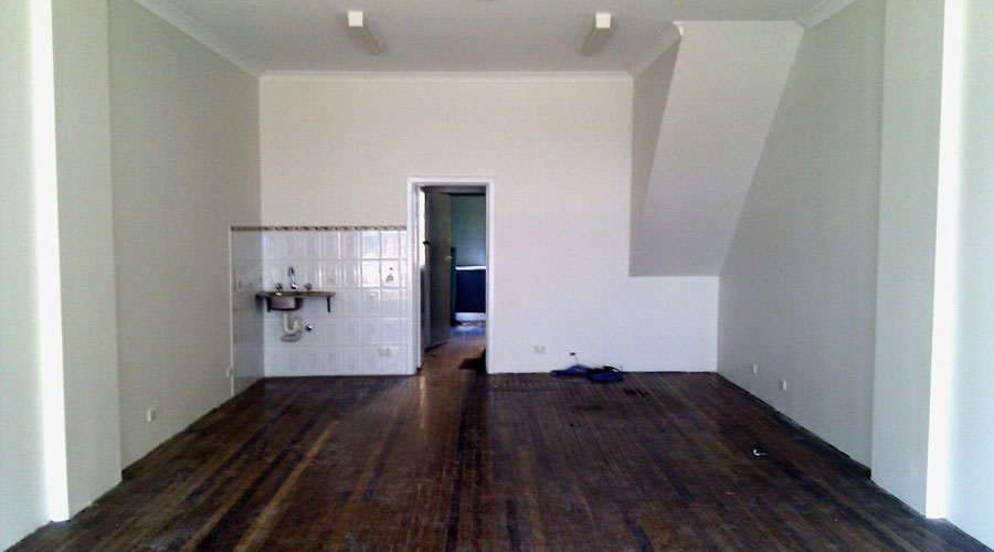 Before: the empty shell interior of the Rockdale premises, bare floorboards and plain walls, prior to the cafe fit-out