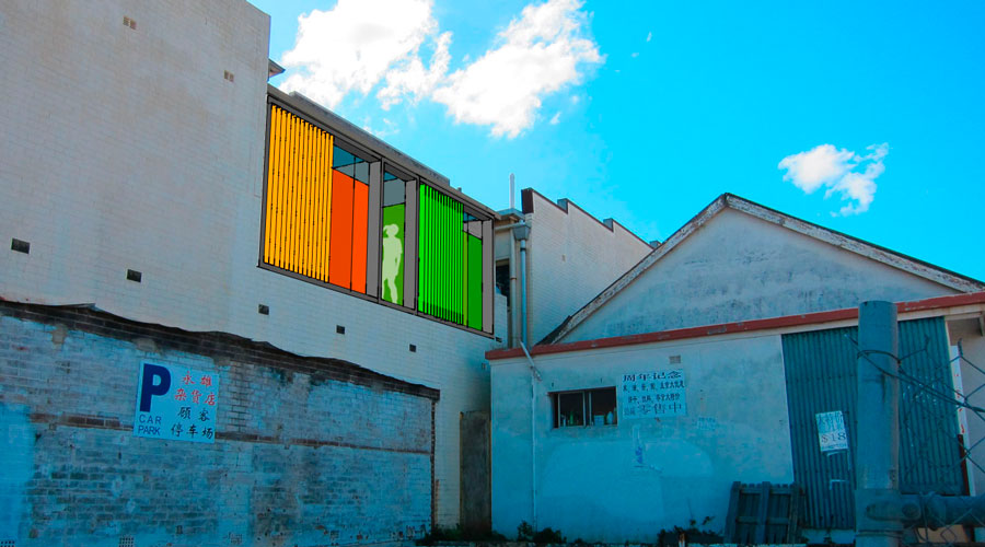 Exterior render of the Youth Zone building's rear laneway facade, showing a new window with orange, red and green vertical battens